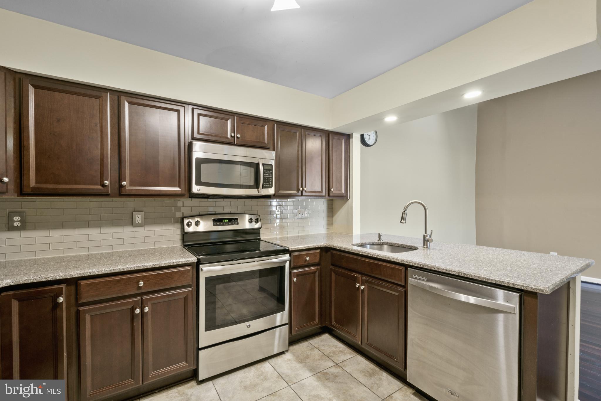 9802 Sailfish Terrace Gaithersburg, MD 20886 - Photo 7 of 18 a kitchen with stainless steel appliances granite countertop a sink stove and microwave