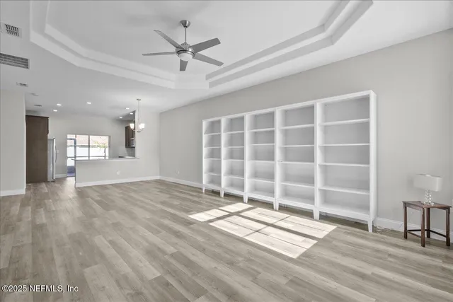 a view of an empty room with a window and wooden floor