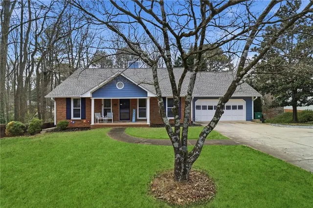 a front view of a house with garden and trees