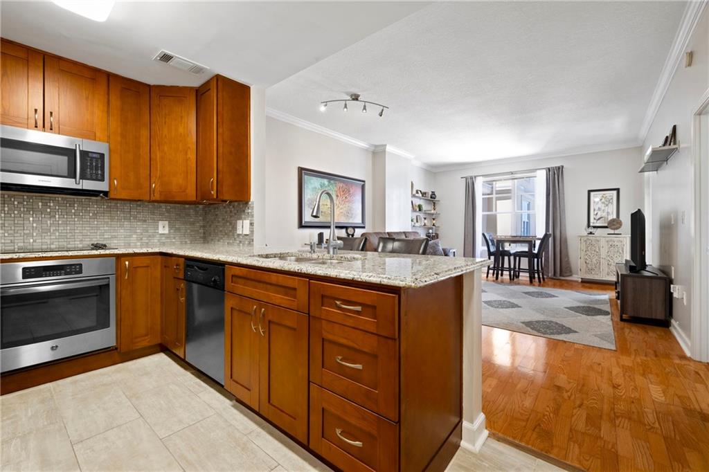 a kitchen with stainless steel appliances granite countertop wooden cabinets a sink a stove a dining table and chairs