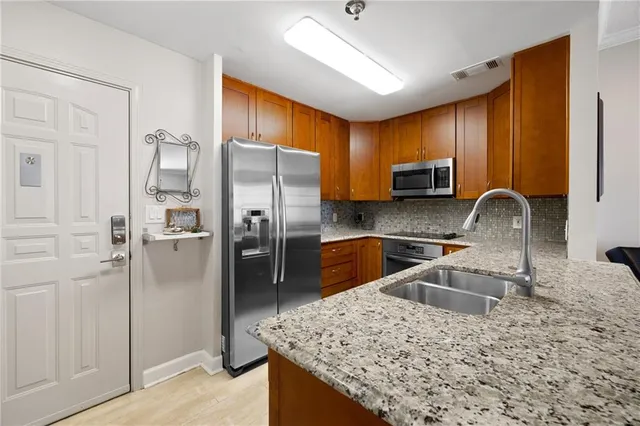 a kitchen with stainless steel appliances granite countertop a refrigerator a stove and a sink