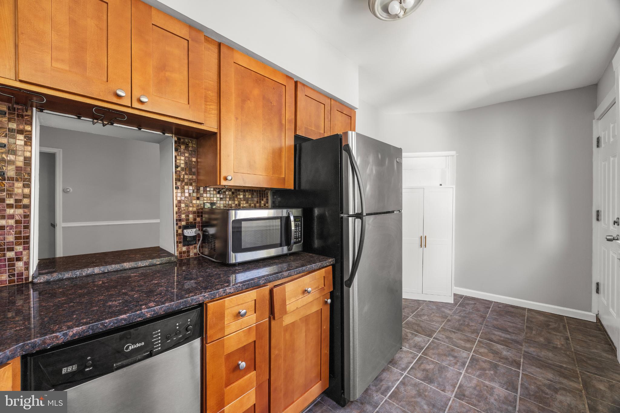 348 Carson Street Philadelphia, PA 19128 - Photo 11 of 27 a kitchen with stainless steel appliances granite countertop a refrigerator a stove and a sink with wooden floor