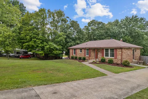a view of a big house with a big yard and large trees