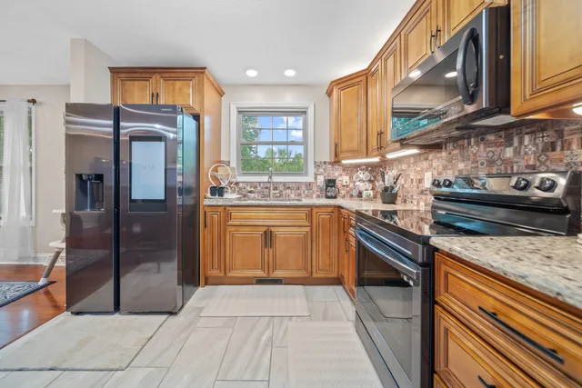 a kitchen with stainless steel appliances granite countertop a stove a sink and a refrigerator