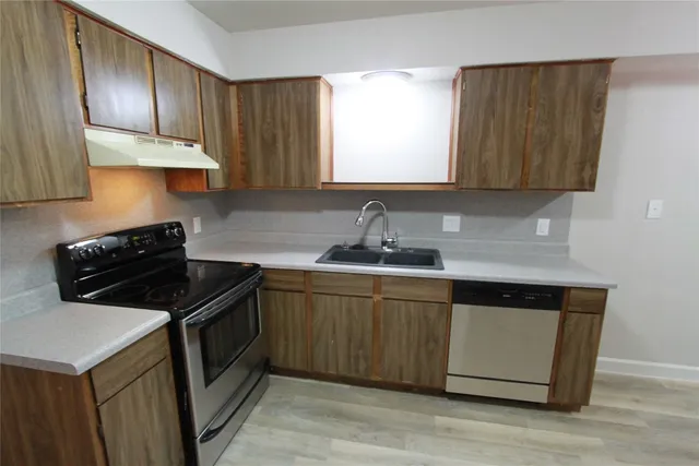 a kitchen with wooden cabinets sink and stove