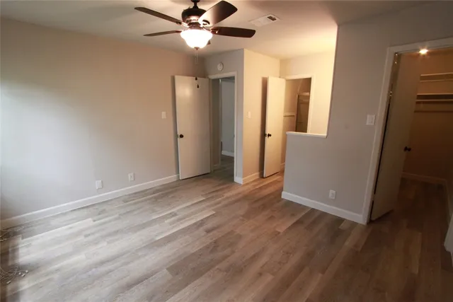 an empty room with wooden floor and a ceiling fan