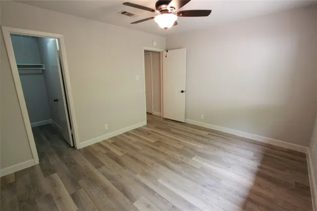 an empty room with wooden floor and fan