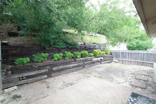 a view of backyard with potted plants and wooden fence