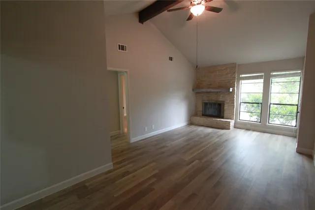an empty room with wooden floor chandelier fan and windows