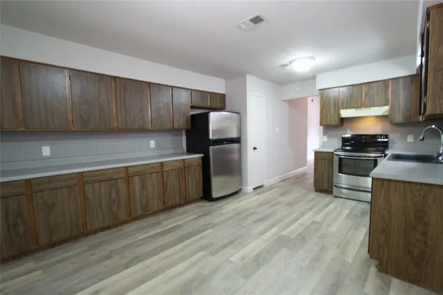 a kitchen with stainless steel appliances granite countertop a stove a sink and a refrigerator
