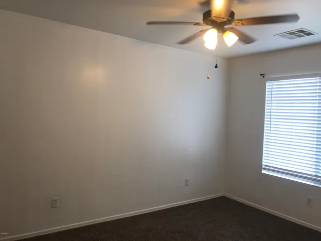 an empty room with a window and fan