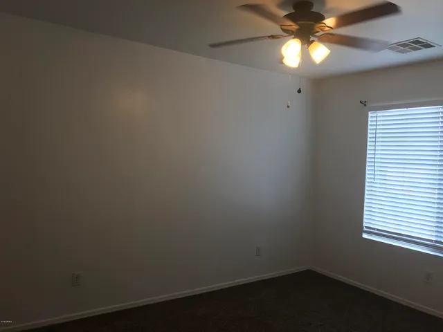 an empty room with a window and a fan