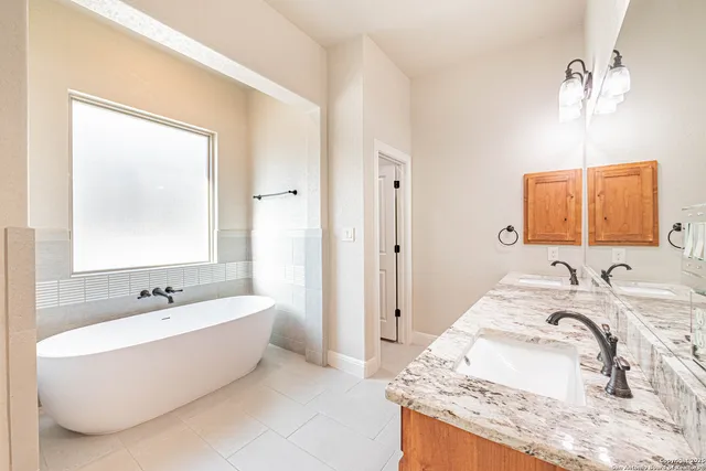a spacious bathroom with a tub sink and mirror