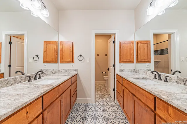 a bathroom with a granite countertop double vanity sink and a mirror