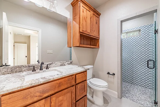 a bathroom with a granite countertop toilet a sink and a mirror