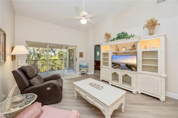 a living room with furniture kitchen view and a wooden floor
