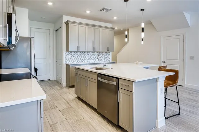 a kitchen with kitchen island a dining table chairs stainless steel appliances and cabinets