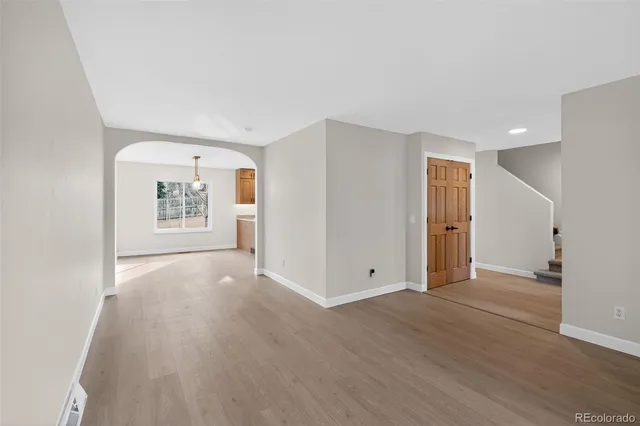 an empty room with wooden floor cabinet and windows