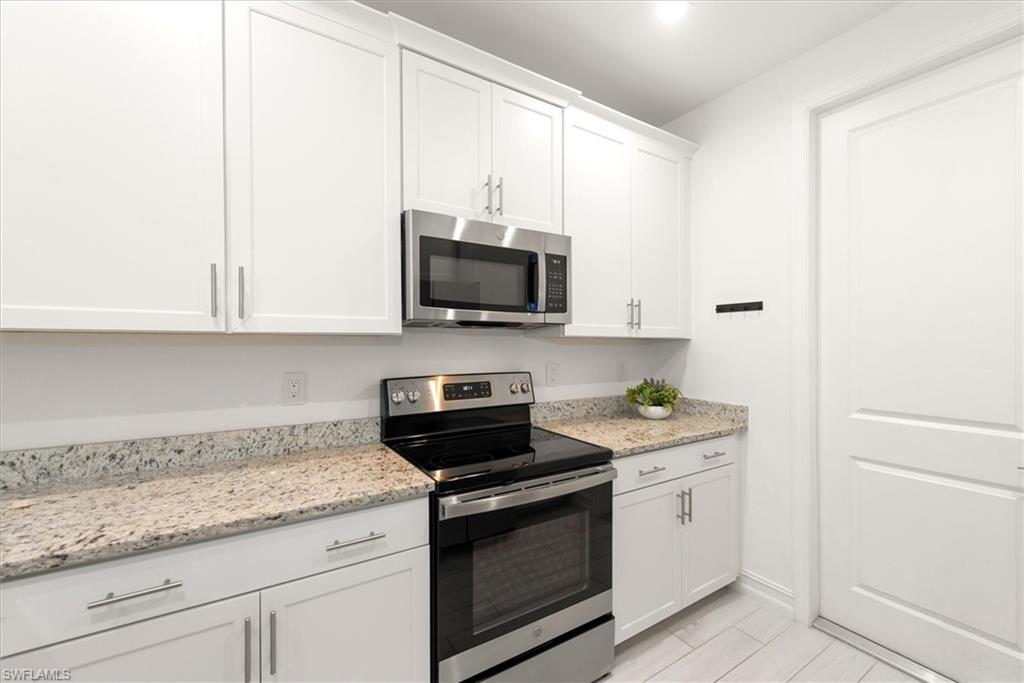 7546 Rockefeller Drive Naples, FL 34119 - Photo 11 of 31 Kitchen featuring appliances with stainless steel finishes, white cabinetry, and light stone counters