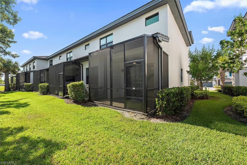 7546 Rockefeller Drive Naples, FL 34119 - Photo 27 of 31 Rear view of house with stucco siding, a lawn, and a residential view