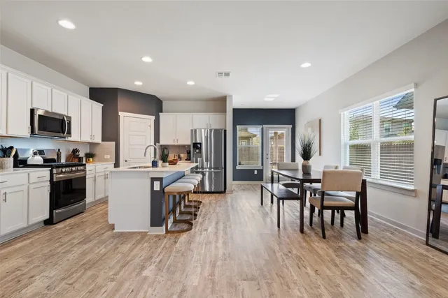 a kitchen with a dining table chairs and refrigerator
