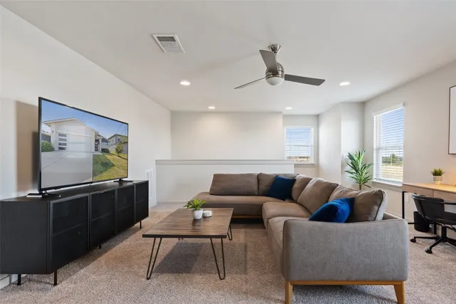 a living room with furniture a flat screen tv and kitchen view