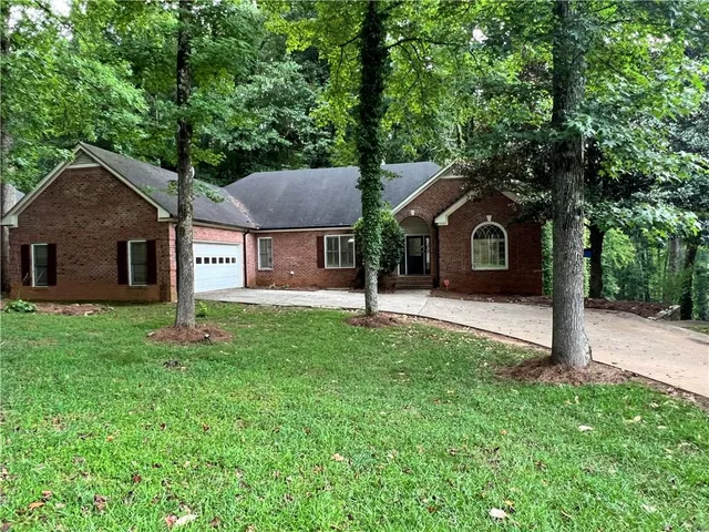 a front view of a house with a garden and trees