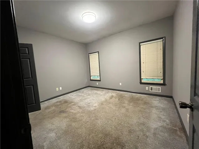 an empty room with wooden floor fireplace and windows