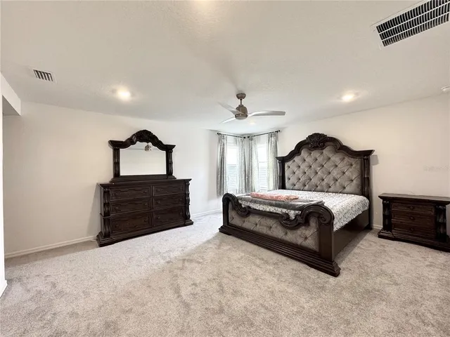a spacious bedroom with a bed and a dresser