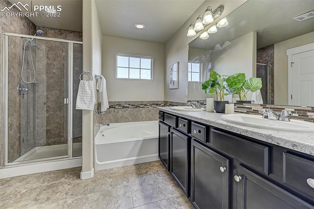 6750 Alliance Loop Colorado Springs, CO 80925 - Photo 21 of 32 a bathroom with a granite countertop sink a large mirror and a bathtub