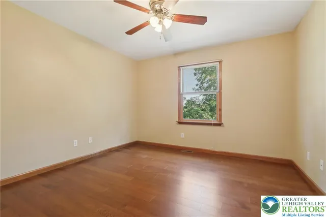 an empty room with a window and a ceiling fan