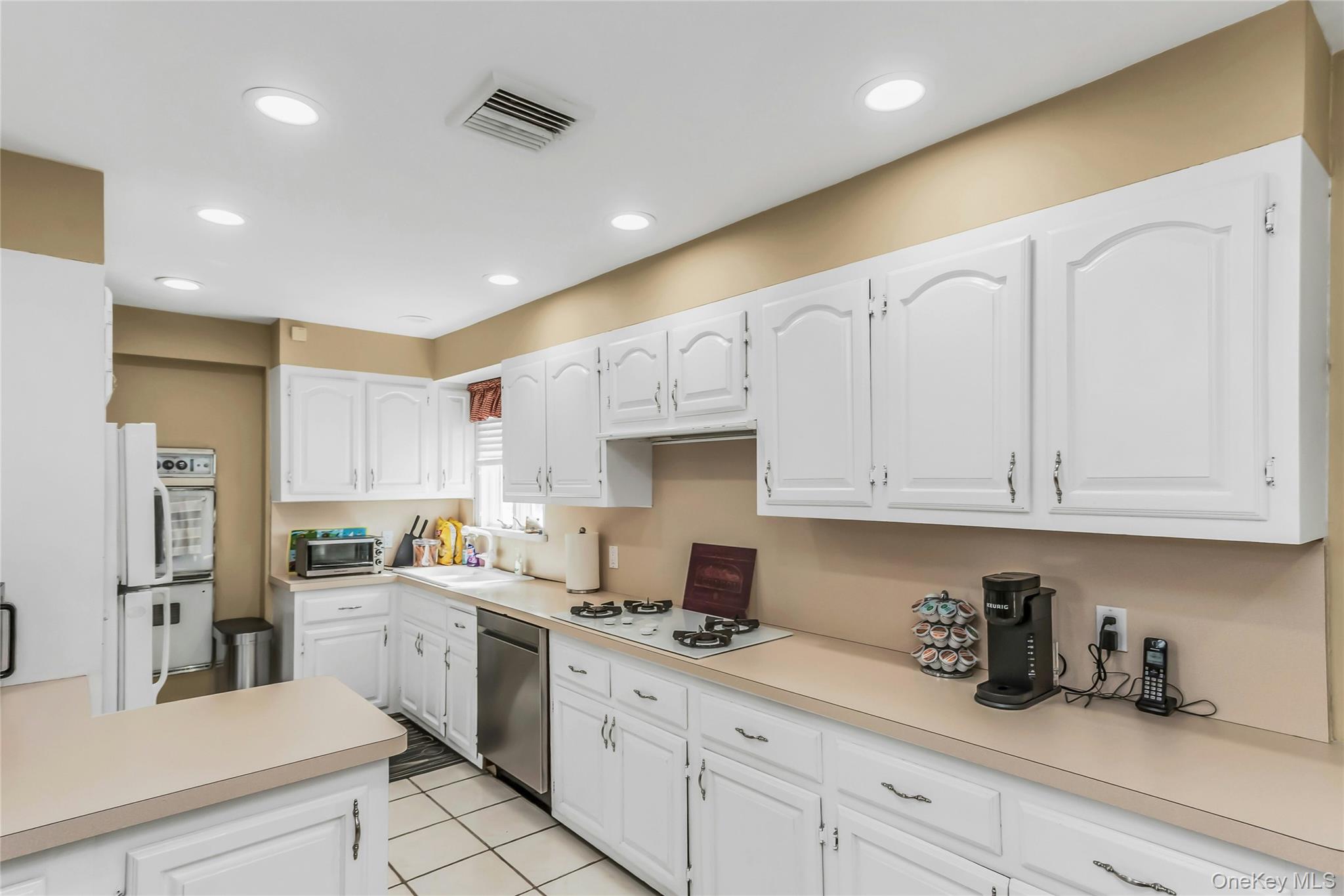 57 Joyce Road Plainview, NY 11803 - Photo 10 of 20 a kitchen with white cabinets and white appliances