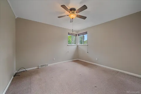 an empty room with a window and a fan
