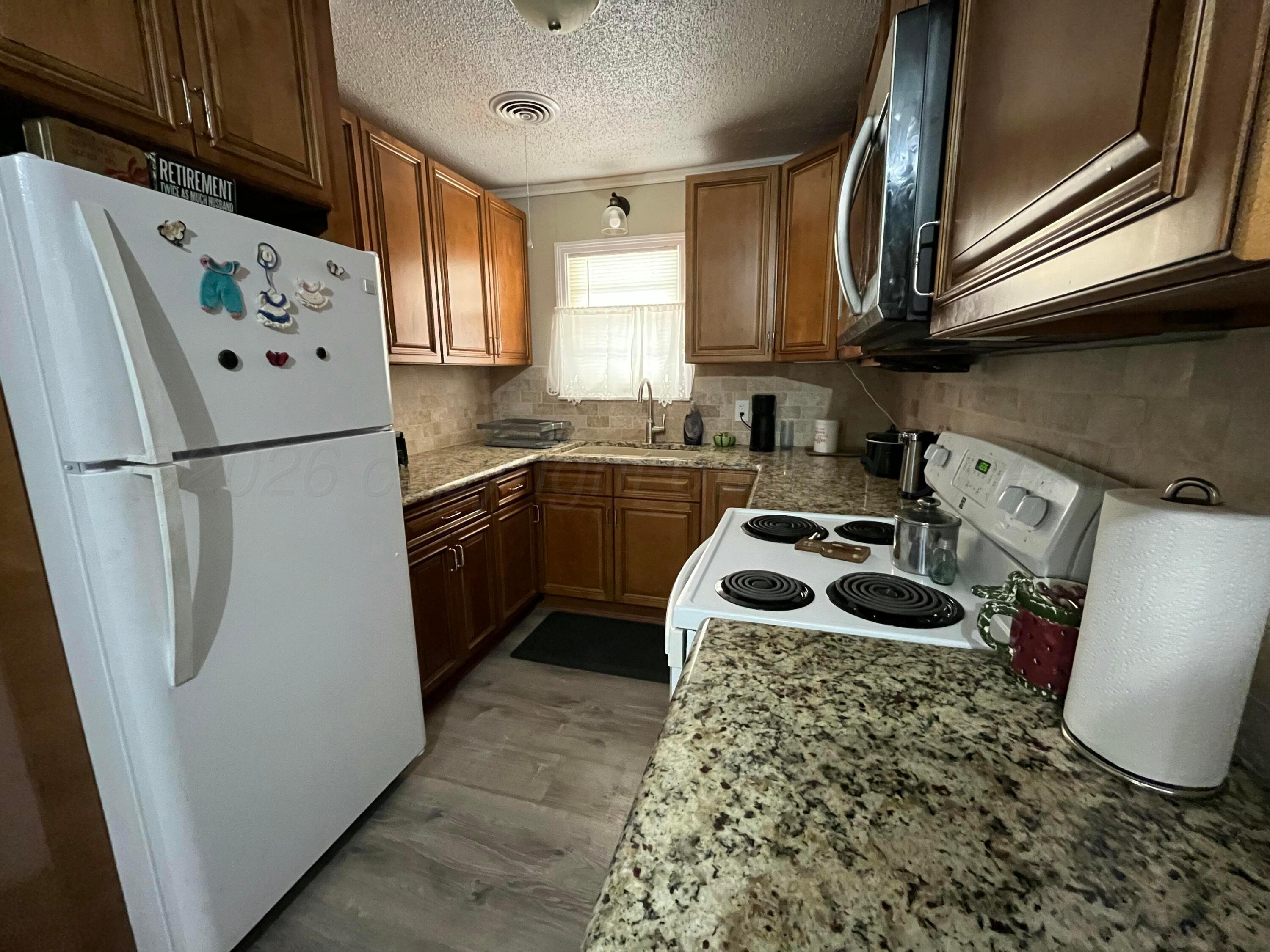 5105 James Avenue Amarillo, TX 79106 - Photo 6 of 21 a kitchen with refrigerator a sink a stove and cabinets