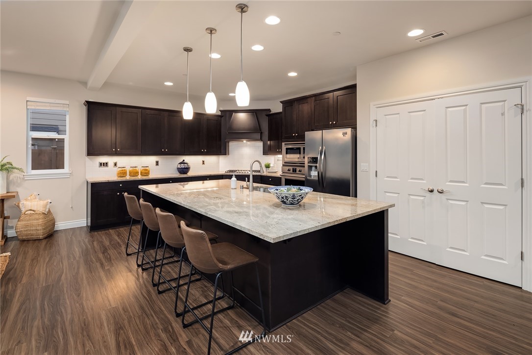 307 221st Place Southwest Bothell, WA 98021 - Photo 7 of 29 a kitchen with stainless steel appliances kitchen island granite countertop a table chairs and a refrigerator