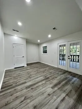 a view of an empty room with wooden floor and a fireplace