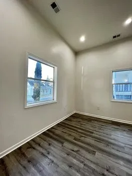 an empty room with wooden floor and windows