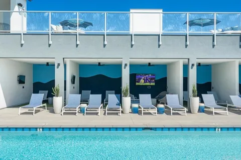 a view of swimming pool with outdoor seating and house in the background