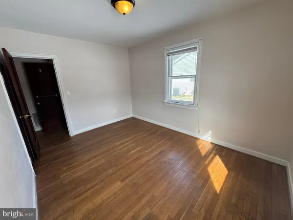 an empty room with wooden floor and natural light