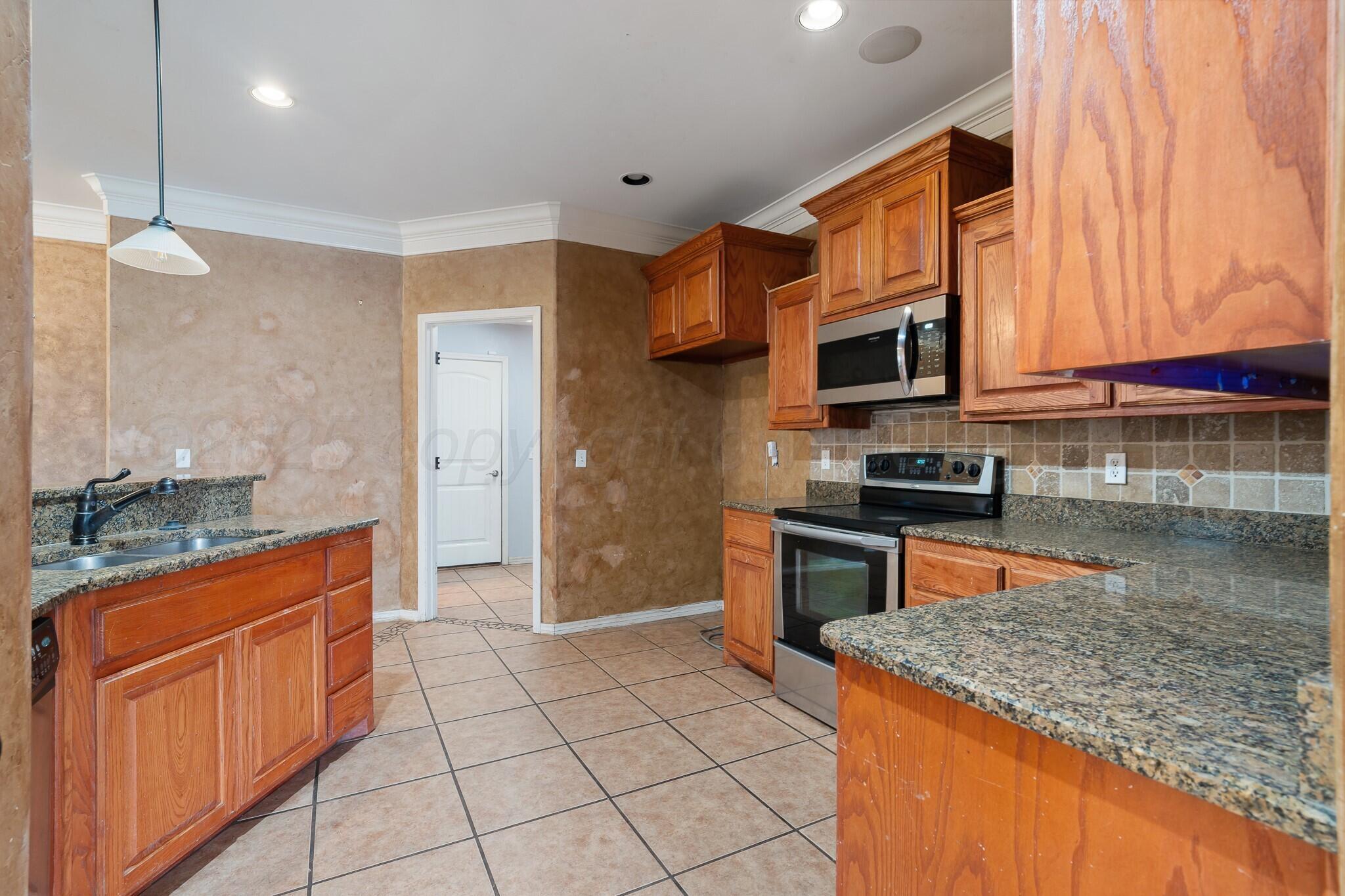 6302 Academy Drive Amarillo, TX 79119 - Photo 4 of 19 a kitchen with stainless steel appliances granite countertop a stove a sink and a microwave