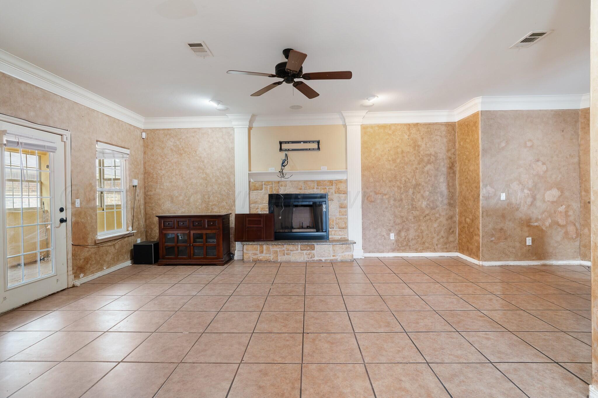 6302 Academy Drive Amarillo, TX 79119 - Photo 7 of 19 a living room with a fireplace furniture a ceiling fan and a window