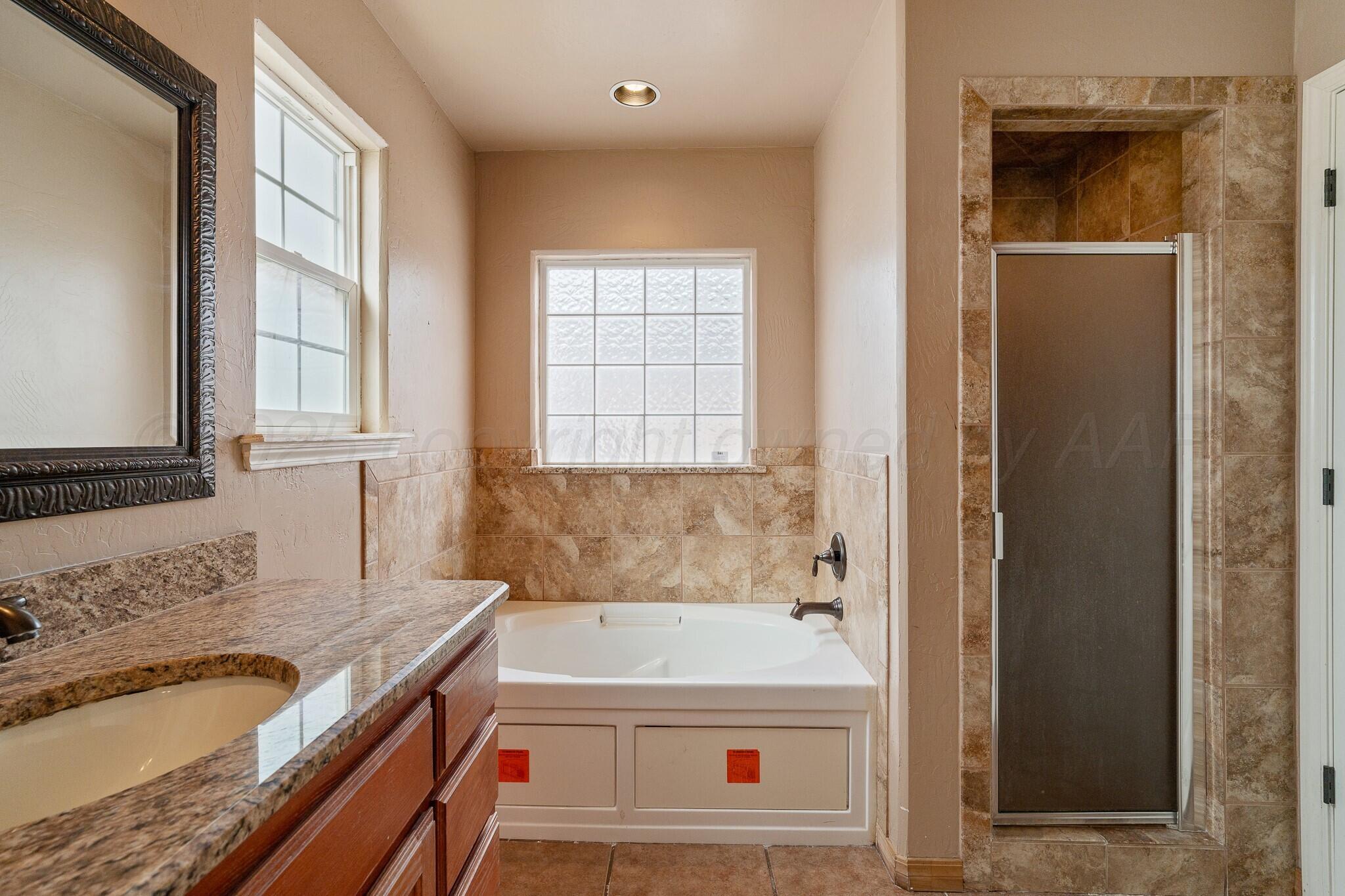 6302 Academy Drive Amarillo, TX 79119 - Photo 10 of 19 a bathroom with a tub a sink and a window