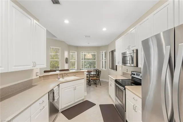 a large white kitchen with a refrigerator a stove a sink and white cabinets