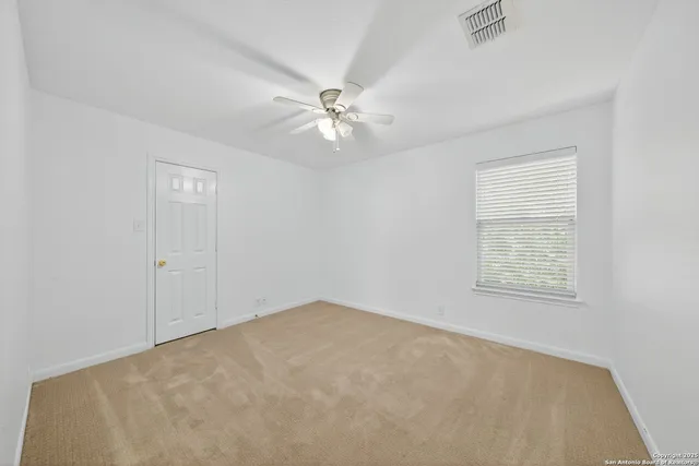 an empty room with windows and fan