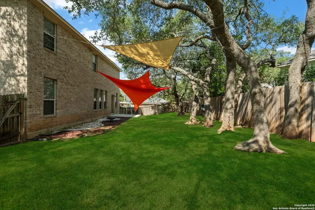 a view of backyard with table and chairs and a large tree
