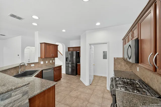 a kitchen with stainless steel appliances granite countertop a sink stove and refrigerator
