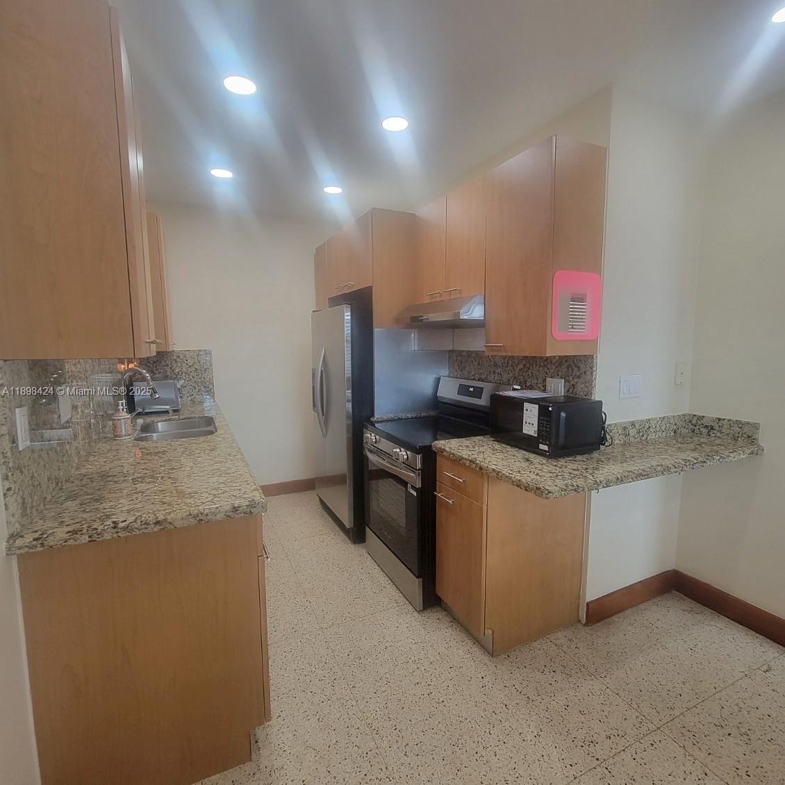 7400 Harding Avenue, Unit 15 Miami Beach, FL 33141 - Photo 3 of 24 a kitchen with stainless steel appliances granite countertop a sink a stove and a refrigerator