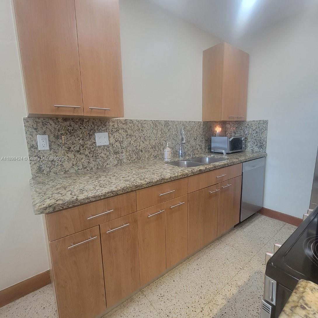 7400 Harding Avenue, Unit 15 Miami Beach, FL 33141 - Photo 5 of 24 a kitchen with stainless steel appliances granite countertop a sink and cabinets