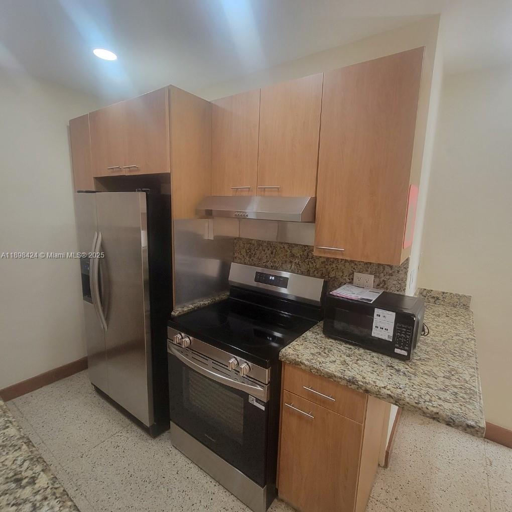 7400 Harding Avenue, Unit 15 Miami Beach, FL 33141 - Photo 8 of 24 a kitchen with granite countertop a sink a stove and a refrigerator