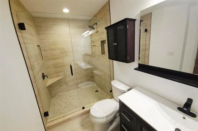 a bathroom with a granite countertop sink toilet and shower